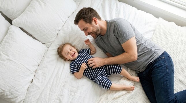 Happy father playing and cuddling with his baby on the bed