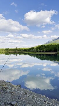 Serene wilderness pond surrounded by dense pine trees with crystal-clear mountain reflections under a dramatic sky