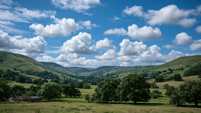 Scenic rolling green hills and valleys with fluffy white clouds in a vast blue sky on a sunny day