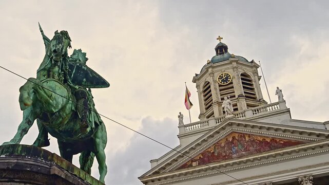 Slow-motion view of Brussels Royal Square with the equestrian statue of Godfrey of Bouillon and the historic Church of St. James on Coudenberg under a dramatic sky.