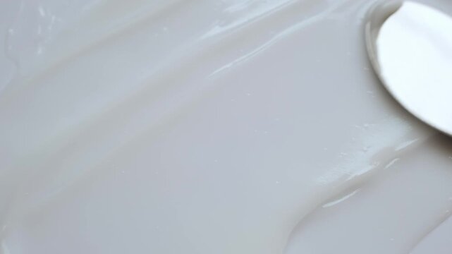 Smooth white cosmetic cream or lotion smeared with metal spatula showing its rich texture