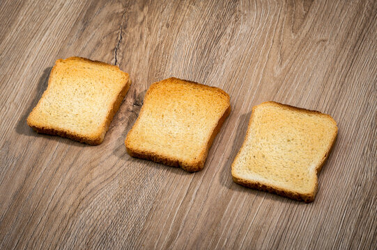 Three golden rusks neatly arranged on wooden surface