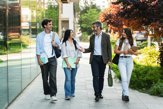University student friends walking together with Professor, talking in the college campus