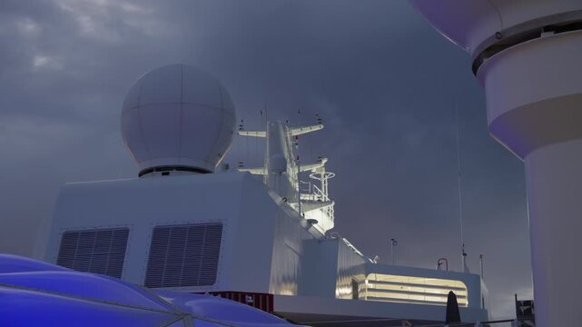 Cruise ship upper deck navigation equipment including white spherical radar dome, communication mast with multiple antennas, and ventilation units under moody overcast twilight sky with purple hues.