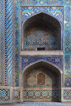 Ornate tiled facade of Nadir Divan Begi Madrasah in Bukhara featuring turquoise and blue mosaic patterns. Ideal for travel publications, cultural heritage content, and architectural design reference.