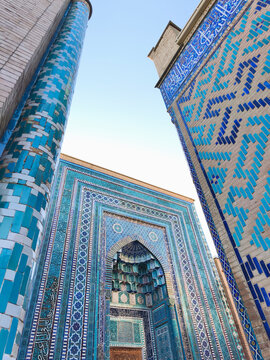 Shah-i-Zinda necropolis facade with intricate blue tilework and muqarnas archway in Samarkand. Ideal for travel publications, cultural heritage materials, and architectural design inspiration.