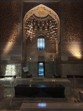 Interior of Gur-e-Amir mausoleum in Samarkand showing ornate muqarnas vault and dark stone cenotaph. Timurid-era Islamic architecture with gilded decoration, ideal for travel heritage publication.