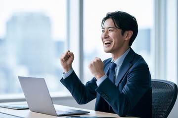 Fototapeta premium パソコンの前で成功を喜びガッツポーズをする日本人男性