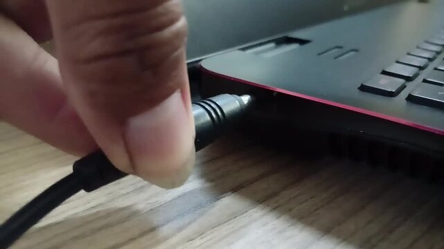 inserting the charger cable in to port charger of a laptop