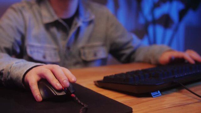 Male Gamer Typing on Illuminated Keyboard While Playing Online