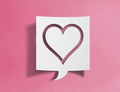 Paper speech bubble with heart outline cutout on pink background, love and social media concept