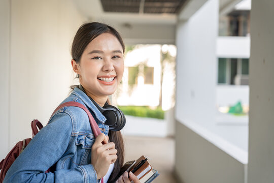 Beautiful student asian woman with backpack and books outdoor. Smile girl happy carrying a lot of book in college campus. Portrait female on international Asia University. Education, study, school