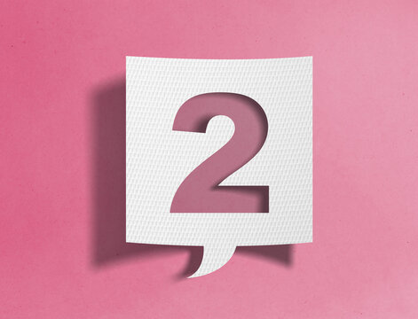 Paper speech bubble with number two cutout on pink background, ranking and sequence concept
