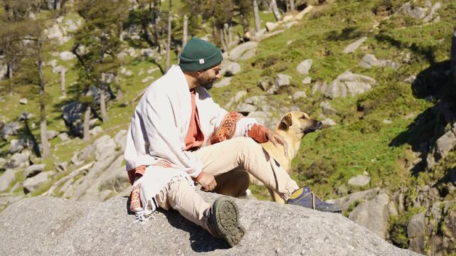 Man sitting with dog on rock. Hiker resting at kasol, Himachal Pradesh.