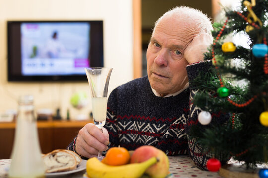 Sad bored older man in warm knitted sweater celebrating Christmas