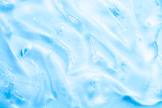 Cosmetic gel, serum, clear sample with a blue tint, close-up. Liquid cream with a foaming texture. Gel texture of a cosmetic product. Liquid cosmetic lotion for skin care.