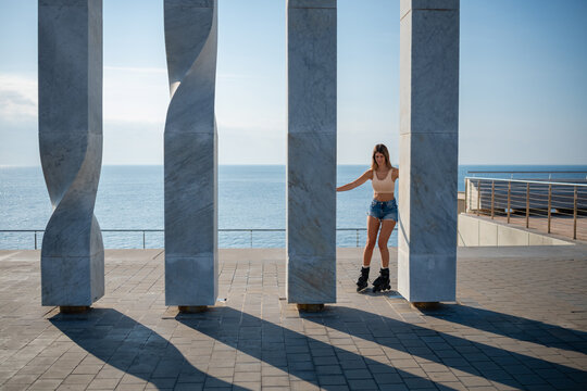 Woman roller skating between columns by the sea