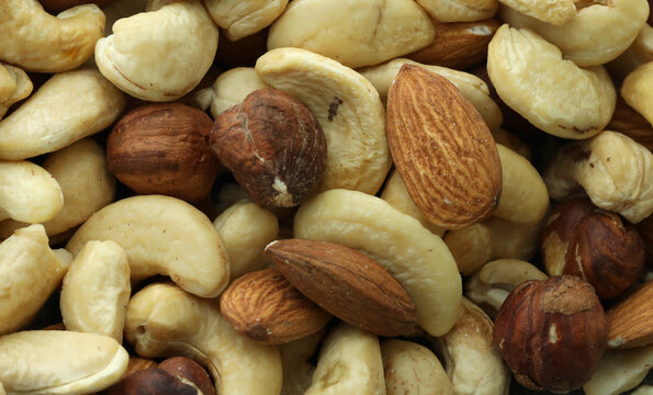 Detailed view on almond and cashew nuts in big pile on table close up