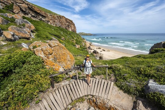 Young pretty woman wearing dress off coast and sea at Robberg Nature Reserve, Plettenberg Bay, South Africa