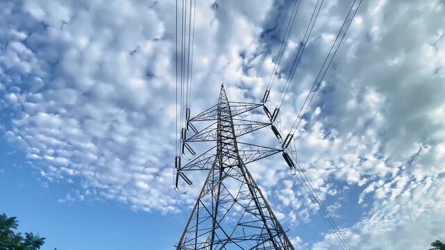 Low-angle wide shot of a high-voltage electricity transmission tower under a clear blue sky in Islamabad, Pakistan. Footage showcasing power infrastructure, electricity transmission, 
