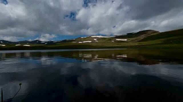Majestic 4K time-lapse of fast-moving clouds and their shadows passing over a pristine blue lake and lush green hills at Kalavan Plateau, Yedig&ouml;ller in Tortum, Turkey