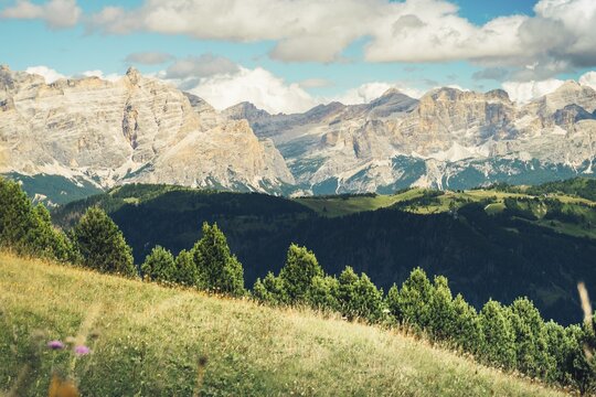 Aerial view Beautiful Dolomites mountain landscape Italy rocky jagged peaks green alpine valley meadows pine trees clouds blue sky scenic summer wilderness nature travel vista