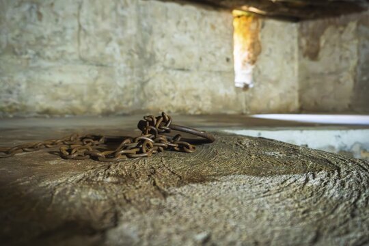Close-up of authentic iron chains and shackles display in underground slave chamber in Mkunazini, Zanzibar. Somber historic artifact in a dimly lit Stone Town dungeon