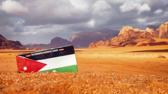 Wadi Rum red sand desert with Jordan flag installation dramatic sandstone mountains colorful sunset clouds iconic Middle East scenery