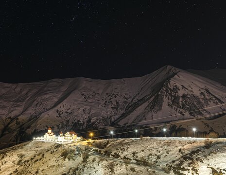 Amaglebis eklesia orthodox church complex at night surounded by mountains and stars in the background. Romantic starry night. Gudauri.Georgia