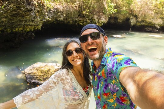 Portrait selfie couple man woman travelers wear vibrant tropical shirt takes pose in Baraka Natural Aquarium. Concept joy, fun and freedom sightseeing secluded Zanzibar turtle sanctuary