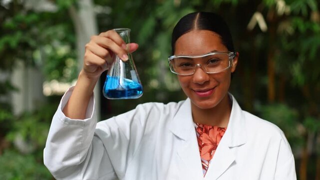 Female scientist mixing blue liquid in a flask for a chemical experiment