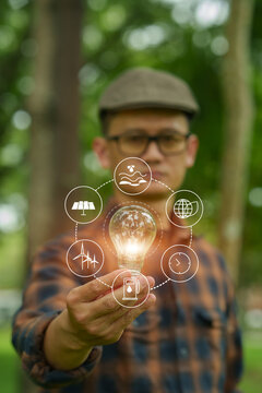 Man Holding Light Bulb with Clean Energy Icons, Illustrating Sustainable Ideas