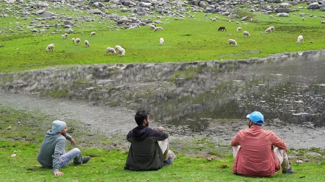 Hikers resting by alpine lake. Travelers exploring parashar Lake, kullu, Himachal Pradesh.