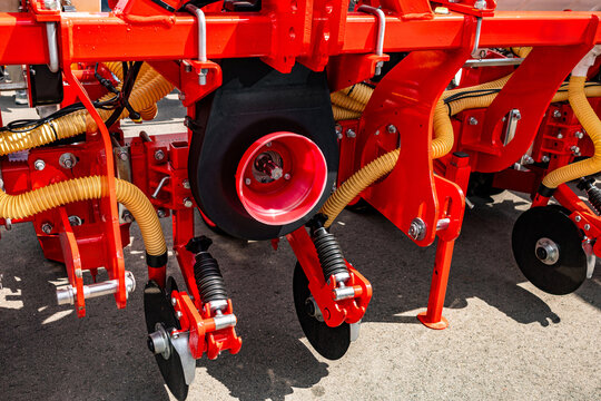 Power take off shaft input and disc coulters on agricultural seeder. Precision planter frame detail featuring pto drive connection, yellow air hoses, tension springs, and hitch mount.