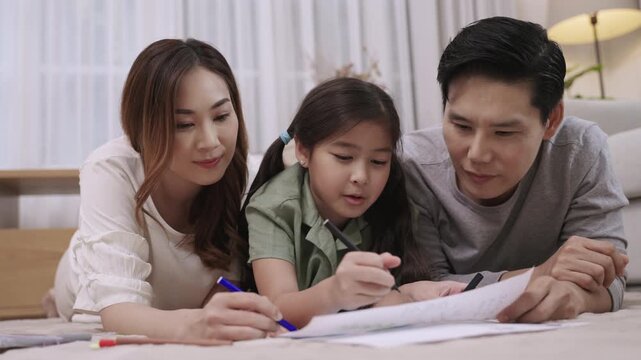 Happy Asian Family Day Concept. Smiling father mother and daughter relaxing and painting on paper together in living room at home. Activity leisure of dad mom and child girl cheerful and fun to draw. 