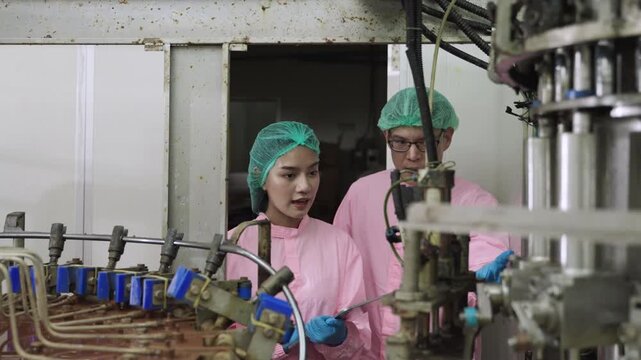 Professional Asian maintenance engineer and technician in food and beverage drink factory in uniform with tablet while talking and discussing machine operation in production line at industry facility.