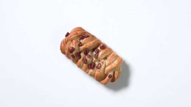 Top view closeup of sweet pecan nut bun rotating on white  background. Colorful sweet pastry perfect for dessert, bakery, cafe concepts. Premium 4K food video