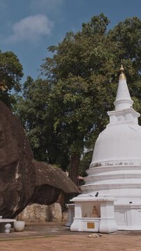 A grand Buddha statue stands tall beside a serene stupa, symbolizing cultural heritage and spirituality in a peaceful landscape. Unawatuna, Sri Lanka. Yatagala RajaMaha Viharaya ancient Buddhist