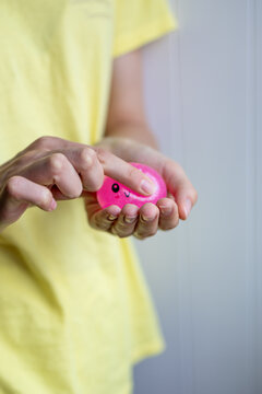 Hands gently press a pink squishy stress toy during sensory play in close-up. Concept of tactile stimulation, focus, stress relief and emotional regulation.