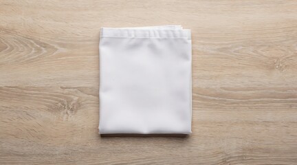 Fototapeta premium Clean white folded t-shirt lying on a light brown wooden table surface.