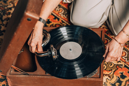 Senior woman using turntable on floor at home