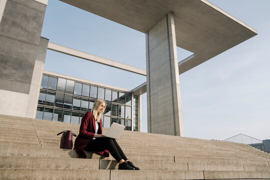 Blond businesswoman with laptop in the background of modern office building