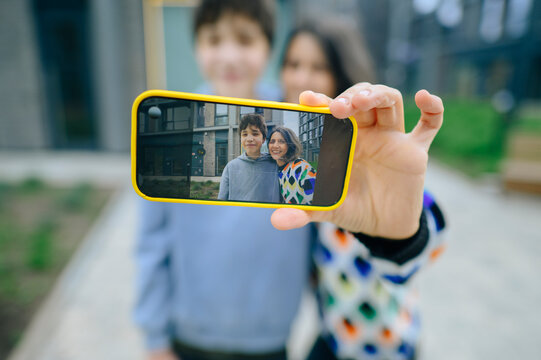 Mother and teenage son take a selfie on a smartphone outdoors