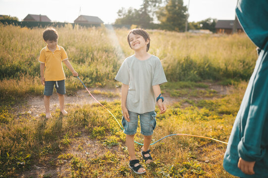 A smiling boy walks over a jumping rope in the summer yard