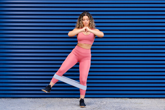 Female sportsperson exercising with resistance band while standing on footpath