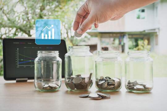 Personal Financial investing strategy with glass jars, coins, digital investment chart, financial growth planning and long-term wealth building on wooden desk with natural home office background