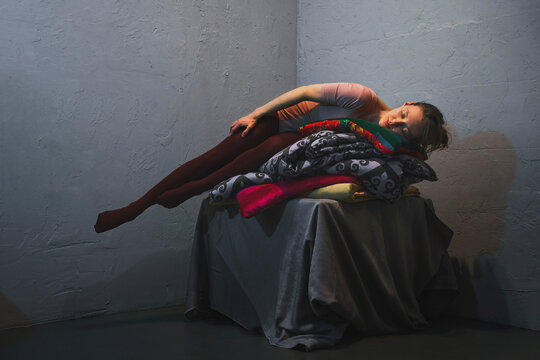 Woman balances on a stack of colorful pillows indoors