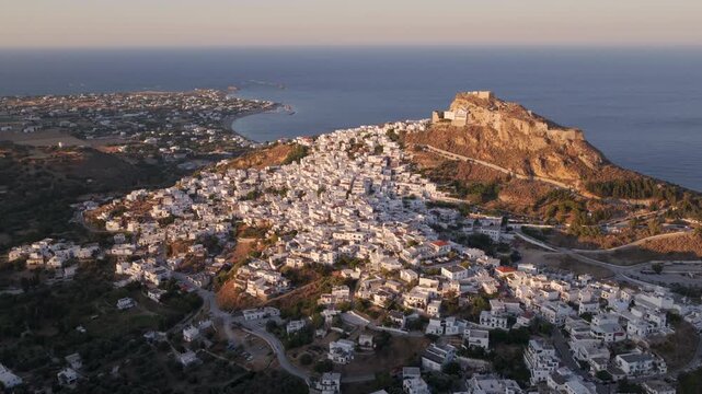 Golden sunset light illuminating the traditional white houses of chora, the main town of skyros island, with its ancient byzantine castle perched on a hill overlooking the aegean sea in greece