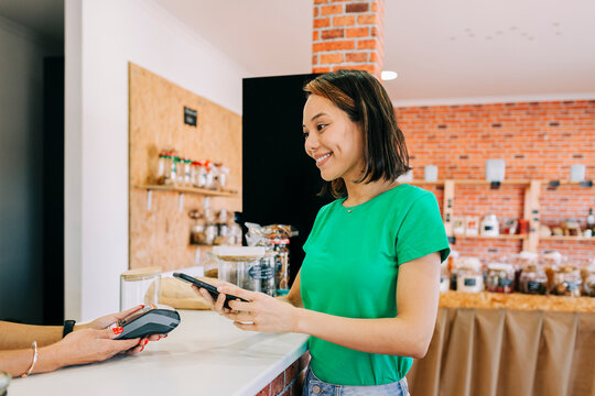 Smiling customer paying with smartphone at checkout in store