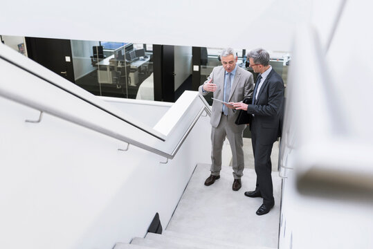 Two businessmen having an informal meeting, using digital tablet